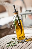 Flasche Olivenöl auf Holztisch im Freien