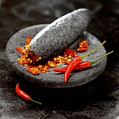 Crushed red peppers in a black volcanic rock mortar