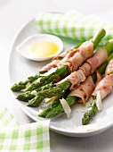 Green asparagus wrapped in bacon with parmesan flakes