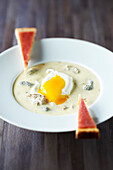 Poached egg in creamy morel sauce,fingers of bread with mountain raw ham