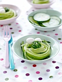 Nest of thin strips of cucumber with mozzarella balls and chives