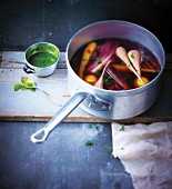 Saucepan of autumn vegetables in broth with Indian mint sauce