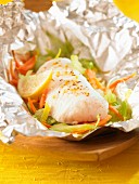 Piece of hake with spices,fennel and lemon cooked in aluminium foil