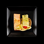 Piece of salmon with stewed fennel and creamy mushroom sauce on a black background