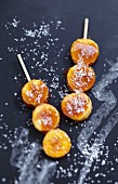 Sliced bananas coated in caramel and grated coconut brochettes