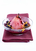 Poached pear in orange syrup with black cherries