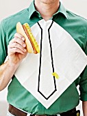 Mann bekleckert seine Krawattenserviette mit Senf beim Essen eines Hotdogs