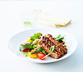 Small grilled sausage skewers with colorful chickpea salad