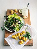 Mixed lettuce and fresh herb salad with white dressing, curried chicken-confit citrus skewers