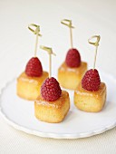 Mini baba cubes topped with raspberries on sticks