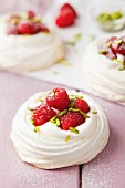 Small meringue nests garnished with raspberries and pistachios