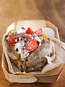 Baked potato stuffed with cheese, anchovies, tomatoes and olives