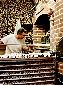 Baker placing bread in a wood oven