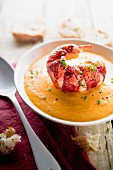 Cream of orange lentil and artichoke soup with a lobster tail