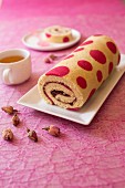 Strawberry jam rolled sponge cake decorated with pink spots
