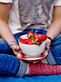 Person holding a bowl of strawberries