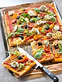 Pizza mit Zwiebelconfit, marinierten Tomaten, Rucola und Mozzarella