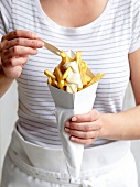 Woman eating a cone full of French fries with mayonnaise