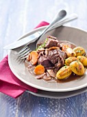 Boeuf Bourgignon (beef in red wine sauce, France) with golden brown, roast garlic potatoes