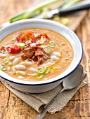 Thick white haricot bean and tomato soup with smoked bacon