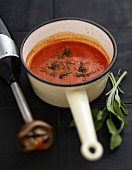 Saucepan of tomato sauce with chopped sage