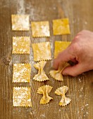 Pinching the squares of pastry in two to shape the farfalle