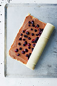 Preparing a sponge roll with chocolate cream and cherries