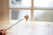 Woman holding a skewer with a piece of bread dipped in melted cheese
