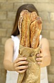 Young girl holding 3 baguettes