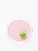 Piece of green tomato on a pink circle