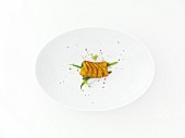 Eine Scheibe Pollackfilet mit Curry und grünen Bohnen auf weißem Teller