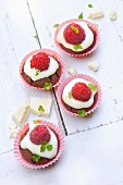 Two chocolate cupcakes topped with a fresh raspberry and mint