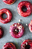 Pile of green tea and blackcurrant donuts topped with crushed almonds and chocolate