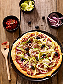 Pizza mit Zucchini, roten Zwiebeln und schwarzen Oliven
