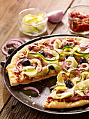 Pizza mit Zucchini, roten Zwiebeln und schwarzen Oliven