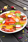 Bunter Salat mit Tomaten, Radieschen, Sesamkörnern und Löwenzahnblüten