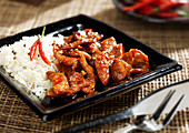 Sautiertes Schweinefleisch mit Chili serviert mit Reis (Asien)