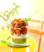 Schichtdessert serviert im Glas mit Mürbeteigkeksen, Frischkäse und Erdbeeren