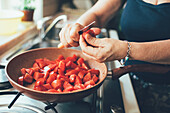 Woman cutting tomatoes in a pan