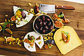 Selection of cheeses with figs, olives and pistachios on a chopping board