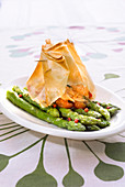 Pan-fried green asparagus with pink pepper and preserved cherry tomatoes, salmon crisp filo pastry purse