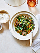 Chickpeas and edamame with fresh herbs in a lamb meatball broth