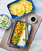 Thai curry with rice and fried pineapple slices in lunch boxes