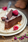 Slice of chocolate truffle cake with ginger cookie crust and raspberries