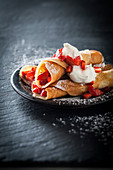 Rolled pancakes garnished with strawberries and whipped cream