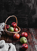 Äpfel auf rustikalem Holztisch und im Weidenkorb