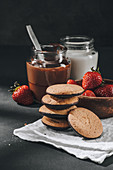 delicious stacked cookies with strawberries and jars of chocolate and milk