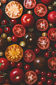 Verschiedene Tomaten, ganz und halbiert (bildfüllend)
