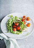 Fish fillet with oven-roasted cherry tomatoes on rocket puree