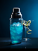 Gefüllter Cocktailshaker vor blauem Hintergrund
